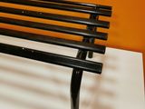 a black bench on a white table against an orange wall