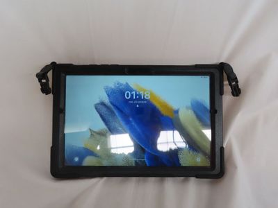 une tablette dont l'écran affiche une image, posée sur un lit