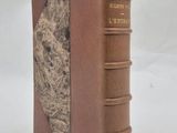 un vieux livre à la couverture brune posé sur une surface blanche
