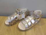 baby girl ' s silver leather sandals with buckles on a wooden surface