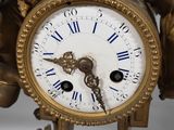 a gold clock with blue roman numerals on it