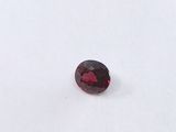 a close up of a red garnet stone on a white surface