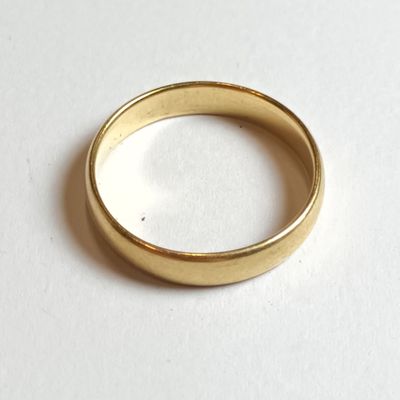 gros plan d'une bague en or sur une surface blanche