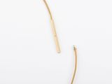 a close up of a gold plated necklace with a curved bar
