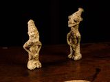 three small figurines sitting on a table next to a piece of bread