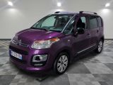 La camionnette violette est garée sur un sol à damier dans un garage.