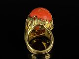 an image of a gold ring with a coral stone in the center