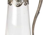 un pichet en verre muni d'une poignée en métal, sur fond blanc