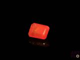 a close up of a red stone on a black surface
