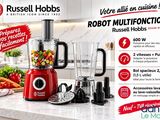un mixeur rouge posé sur un plan de travail, à côté d'un tas de légumes