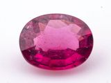 un gros plan d'une pierre précieuse rose de forme ovale posée sur une surface blanche