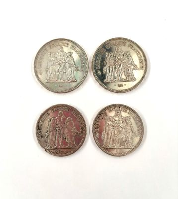 quatre types différents de pièces d'argent sur une surface blanche