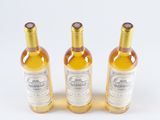 three bottles of white wine sitting on top of a white surface