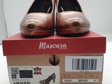 La boîte à chaussures est ouverte, laissant apparaître une paire de chaussures métalliques.