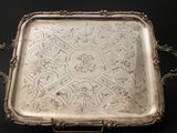 an antique silver tray with ornate designs on it on a black surface