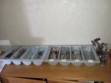 several trays of utensils are lined up on a wooden table