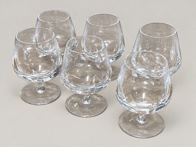 quatre verres à vin vides posés sur une surface blanche