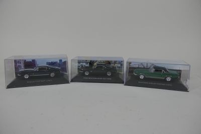 trois voitures miniatures sont exposées dans une vitrine posée sur une surface blanche