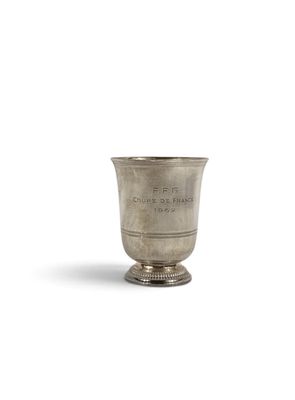 une vieille coupe en argent posée sur une surface blanche