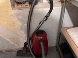 a vacuum that is sitting on the floor next to a shelf