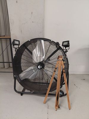 un ventilateur posé dans une pièce, avec un trépied à côté