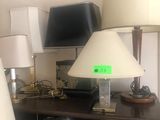 several lamps are on a shelf in a room with a television