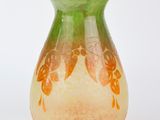 un vase vert et orange posé sur une surface blanche