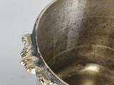 a silver pot sitting on a white surface