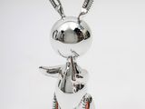 figurine de lapin en métal argenté posée sur une surface blanche, avec un fond blanc