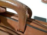 une personne tenant un sac en cuir marron muni d'une poignée