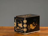 une boîte noire et dorée posée sur une table en bois