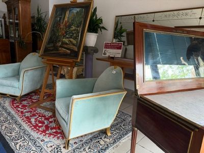 two chairs in a room with paintings on the wall