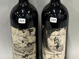 two bottles of red wine sitting next to each other on a table