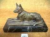 statue d'un chien posée sur un socle en marbre, sur lequel est accrochée une étiquette