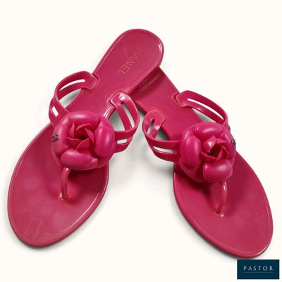 une paire de sandales roses ornées de nœuds, posées sur un fond blanc