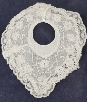 an old white lace bib with a hole in the middle of it