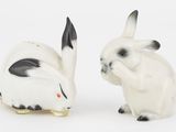 deux figurines de lapins, l'une blanche et l'autre noire, assises l'une à côté de l'autre