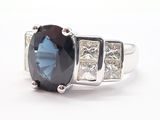 an image of a ring with a large blue stone surrounded by three smaller diamonds