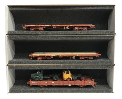 trois petits trains miniatures dans une vitrine, sur fond blanc