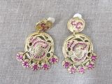 a pair of earrings with pink stones and pearls