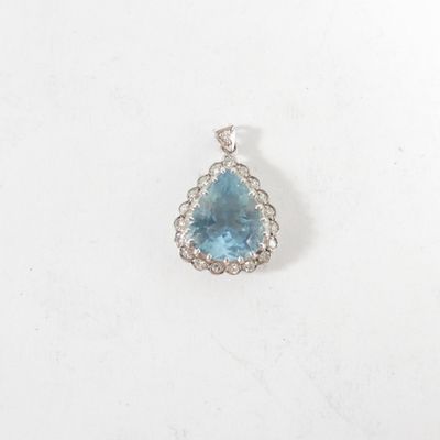 un gros plan d'un pendentif composé d'une topaze bleue et de diamants, sur fond blanc