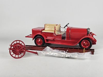 a red toy car on a train track with a red wagon