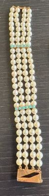 collier composé de perles de verre blanches et de perles vertes, monté sur un support en bois