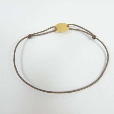 a close up of a bracelet with a gold disc on a white background