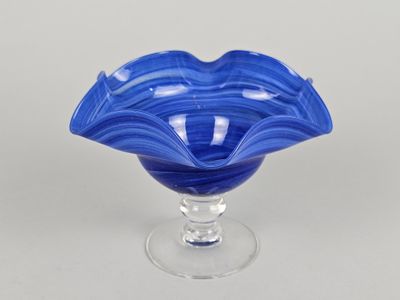 une image représentant un bol en verre bleu posé sur un socle transparent