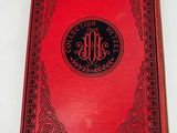 an old red book sitting on top of a white table