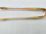 gold plated pin with a curved handle on a white surface