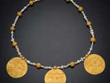un collier composé de pièces d'or et de perles sur fond noir