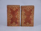 a pair of red and gold leather books with gold trim