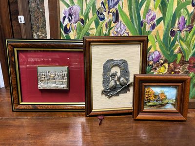 trois photos encadrées posées sur une table à côté d'un tableau